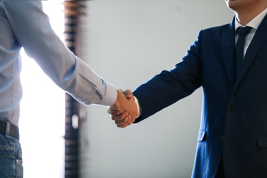 Photo of Male lawyer shaking hands with client in office, closeup