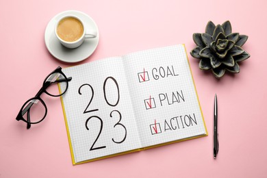 Photo of Flat lay composition of notebook with text 2023 Goal, Plan, Action on pink background. New Year aims