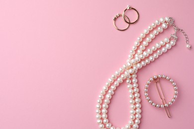 Elegant pearl jewelry on pink background, flat lay. Space for text