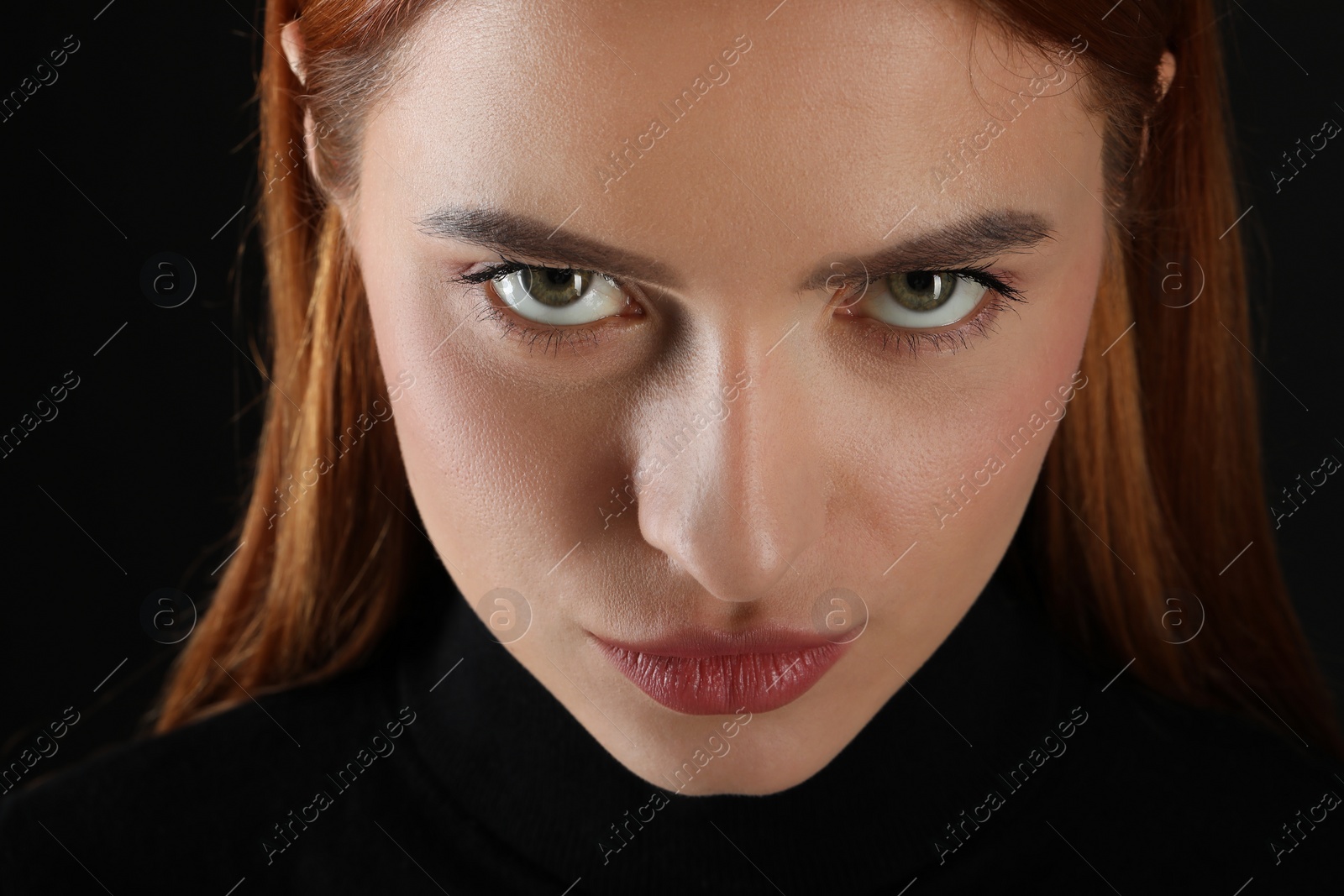 Photo of Evil eye. Young woman with scary eyes on black background, closeup