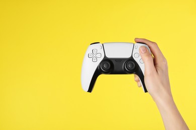 Photo of Woman with game controller on yellow background, closeup. Space for text