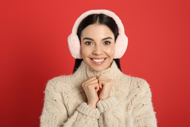 Photo of Beautiful young woman wearing earmuffs on red background