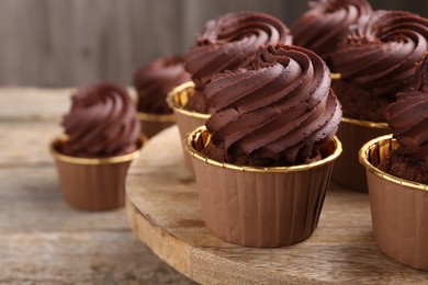 Photo of Delicious chocolate cupcakes on wooden table, closeup