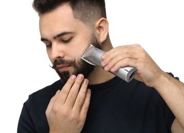 Photo of Handsome young man trimming beard on white background