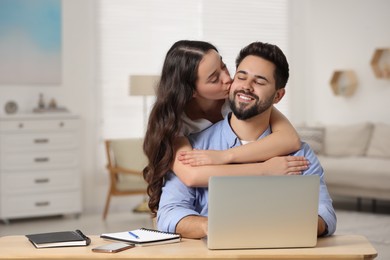 Cute couple. Woman kissing her smiling boyfriend at home, space for text