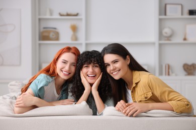 Portrait of happy young friends on sofa at home