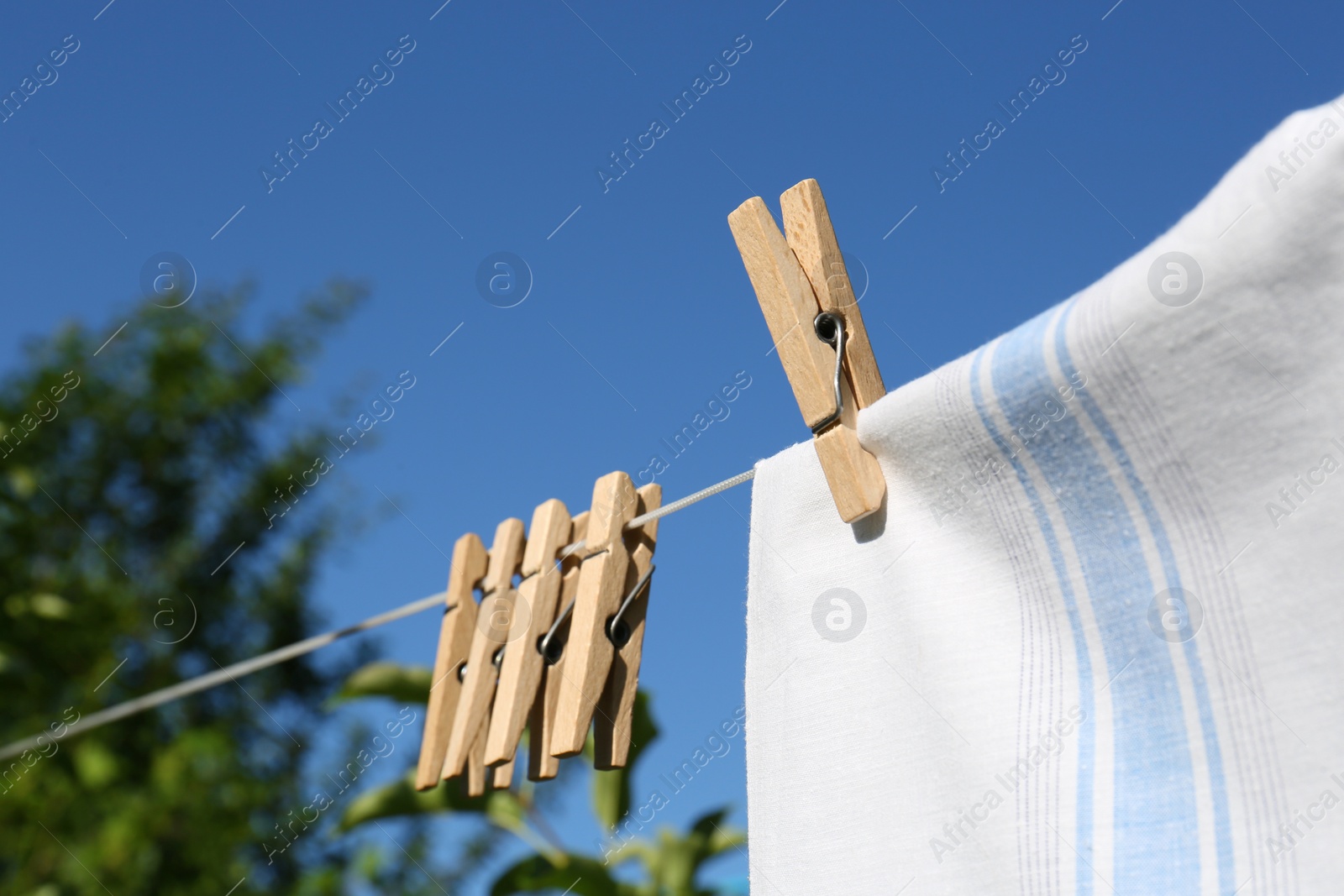 Photo of Washing line with clean laundry and clothespins outdoors, closeup