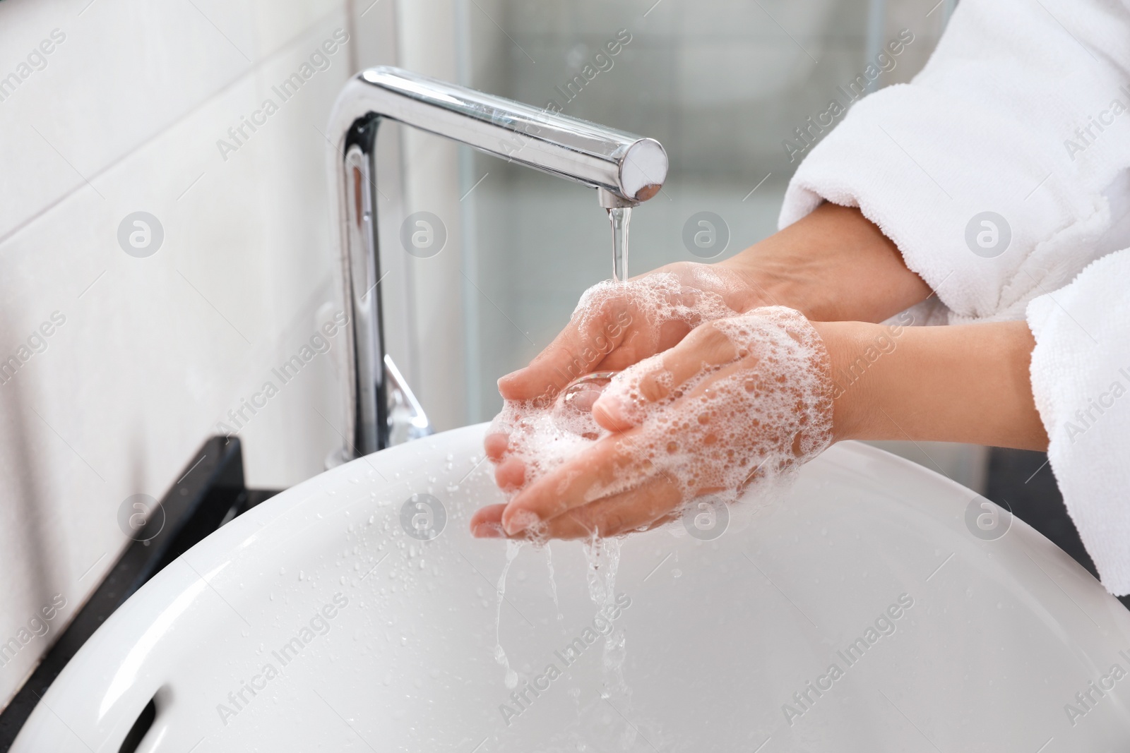 Photo of Woman washing hands with soap over sink in bathroom, closeup