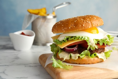 Tasty burger with fried egg on wooden board, space for text