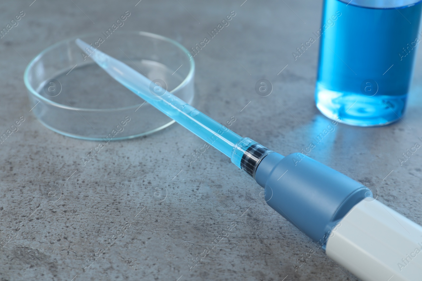 Photo of Laboratory analysis. Micropipette, petri dish and beaker on grey table, closeup