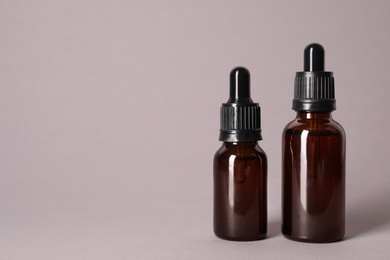Photo of Cosmetic bottles of essential oils on color background. Space for text