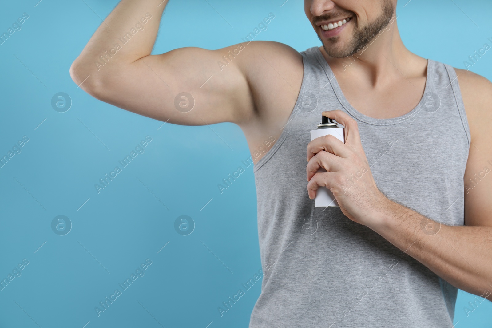 Photo of Man applying deodorant on turquoise background, closeup. Space for text