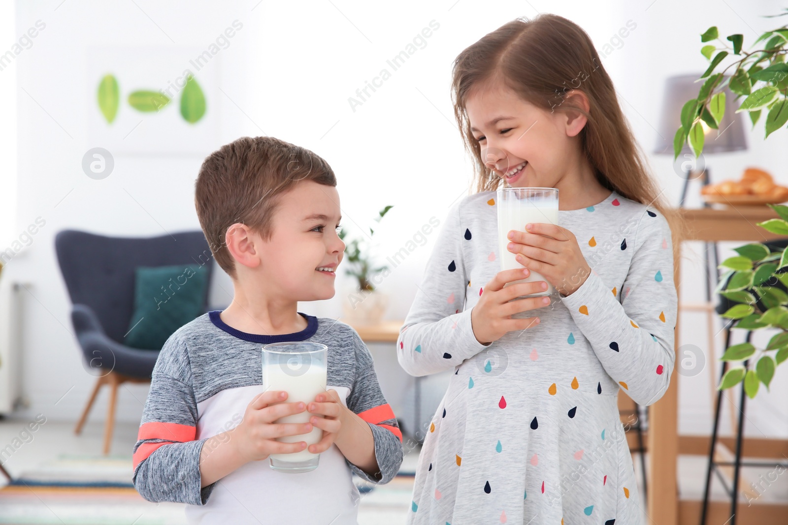 Photo of Cute little kids with glasses of milk indoors