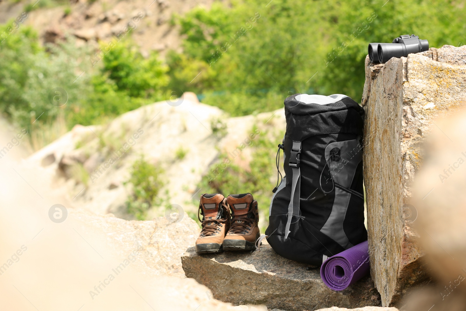 Photo of Backpack and camping equipment on rocks in wilderness. Space for text