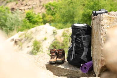 Backpack and camping equipment on rocks in wilderness. Space for text