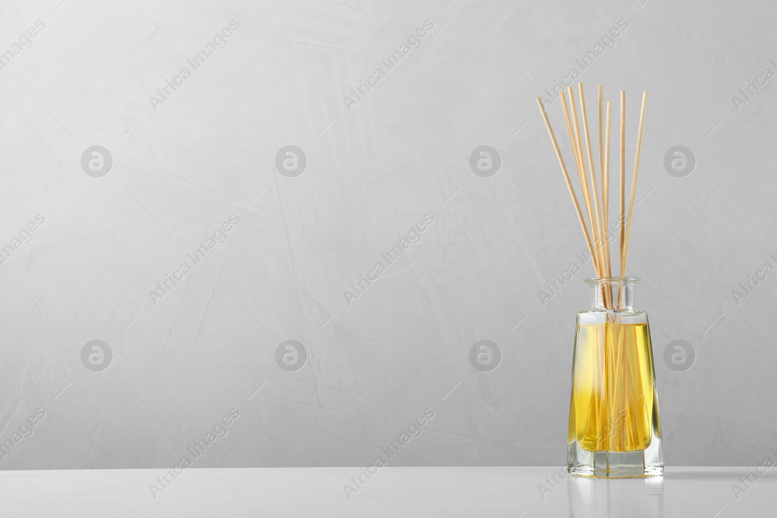 Photo of Reed air freshener on table against grey background, space for text