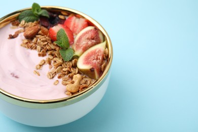 Photo of Bowl with yogurt, fruits and granola on light blue background, closeup. Space for text