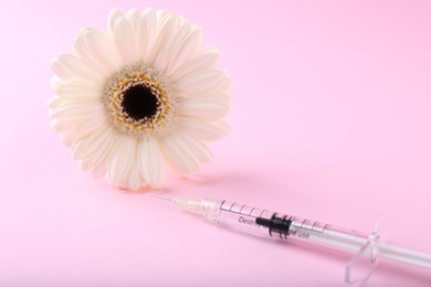 Photo of Cosmetology. Medical syringe and gerbera flower on pink background, closeup