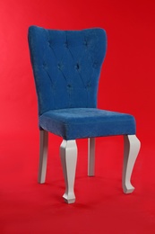 Photo of Stylish blue chair on red background. Element of interior design