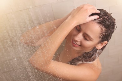 Photo of Happy woman washing hair while taking shower at home, above view