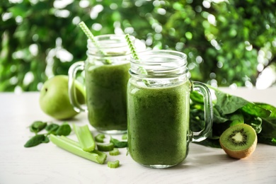 Photo of Delicious green juice and fresh ingredients on white table