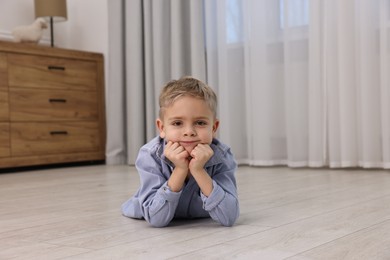 Photo of Cute little boy lying on warm floor at home. Heating system