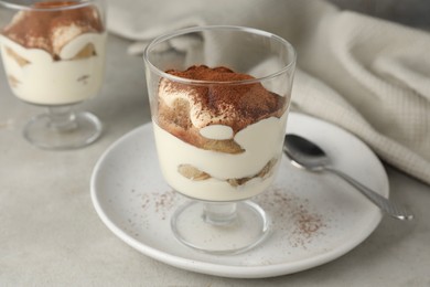 Photo of Delicious tiramisu in glass on light table