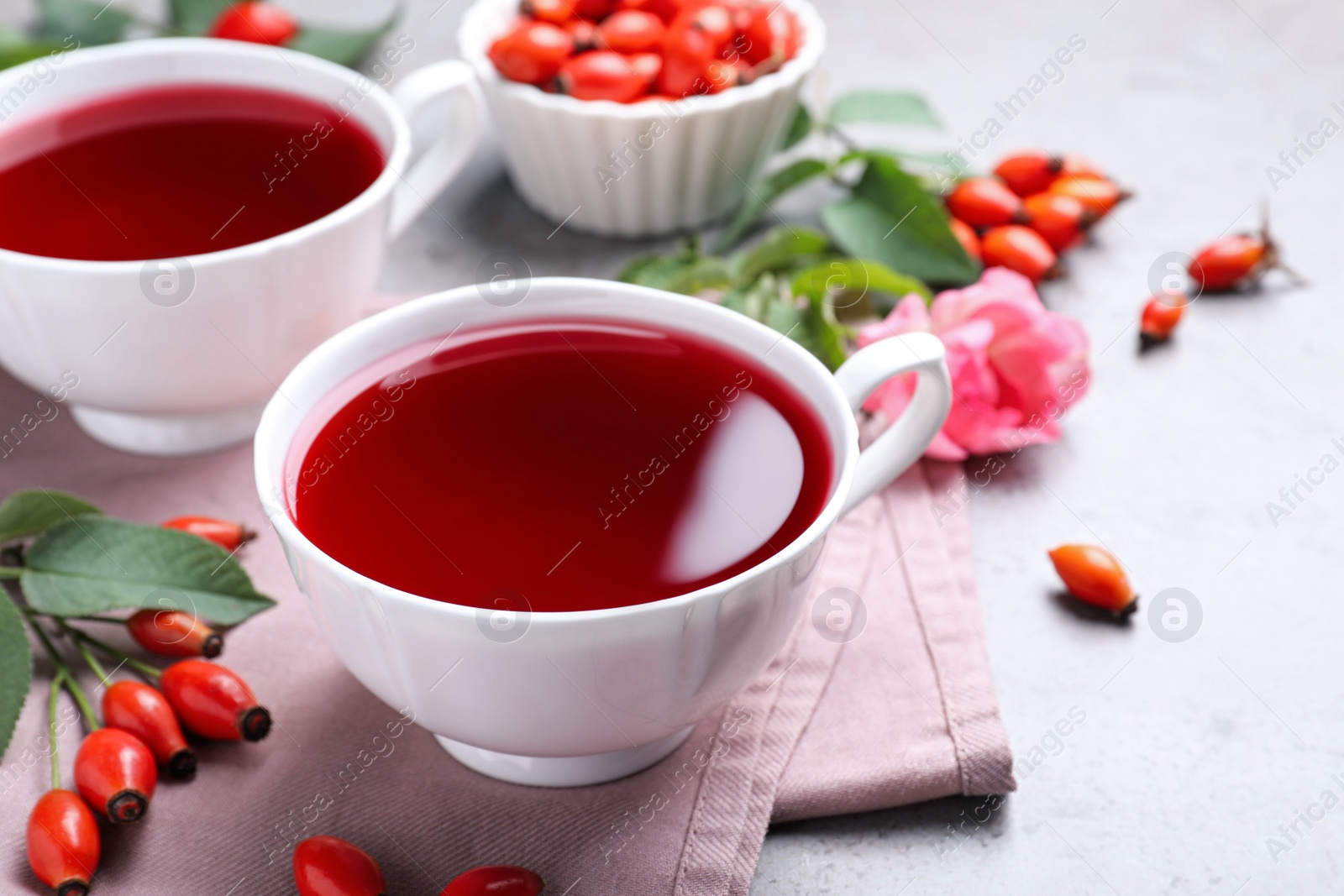 Photo of Fresh rose hip tea and berries on light table, closeup