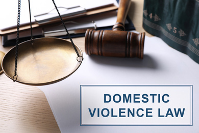 Image of Blank paper sheets, scale and gavel on wooden table, closeup. Domestic violence law 