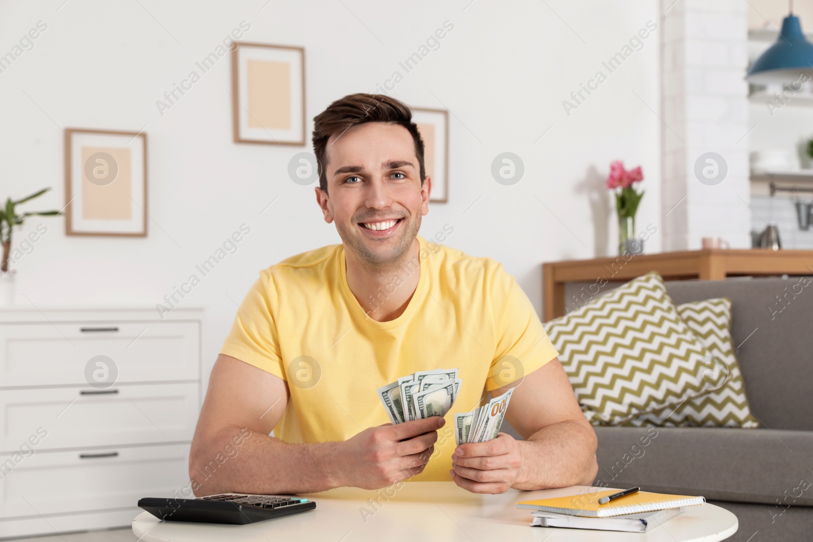 Photo of Happy man with money at table in living room