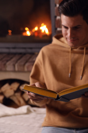 Man reading book near fireplace at home