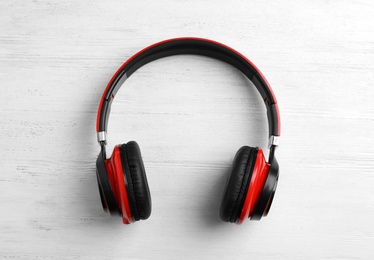 Photo of Stylish modern headphones with earmuffs on wooden background, top view