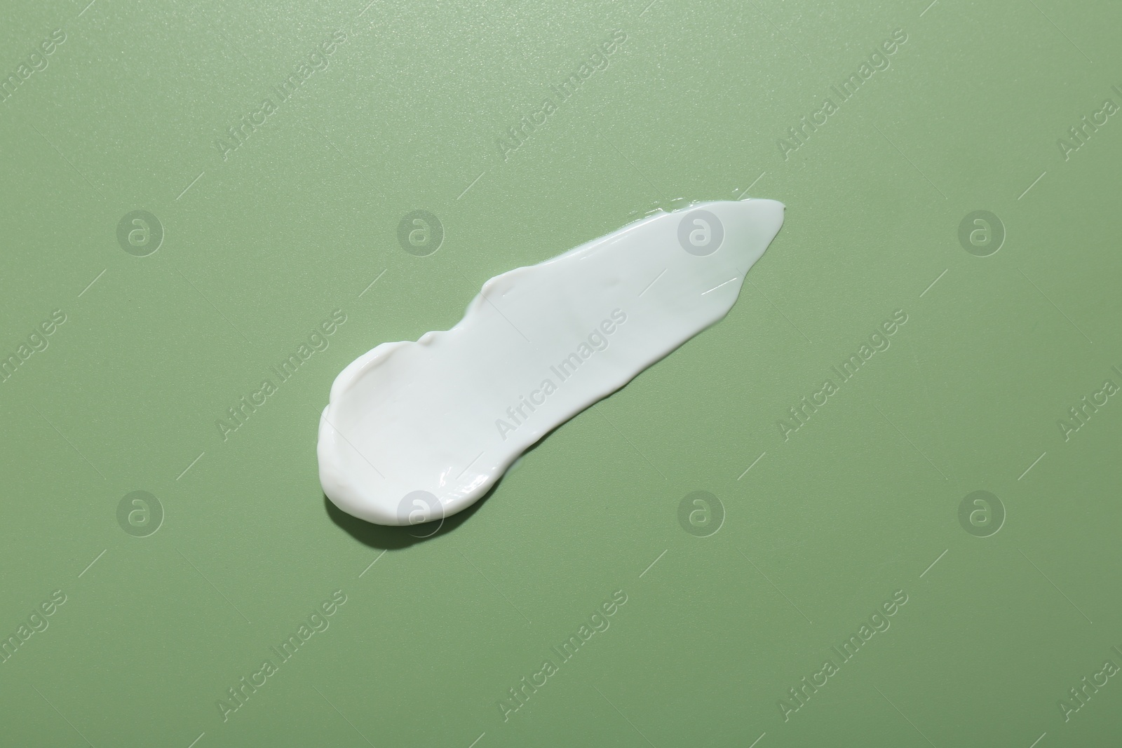 Photo of Sample of face cream on green background, top view