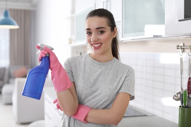 Young woman with bottle of detergent in kitchen