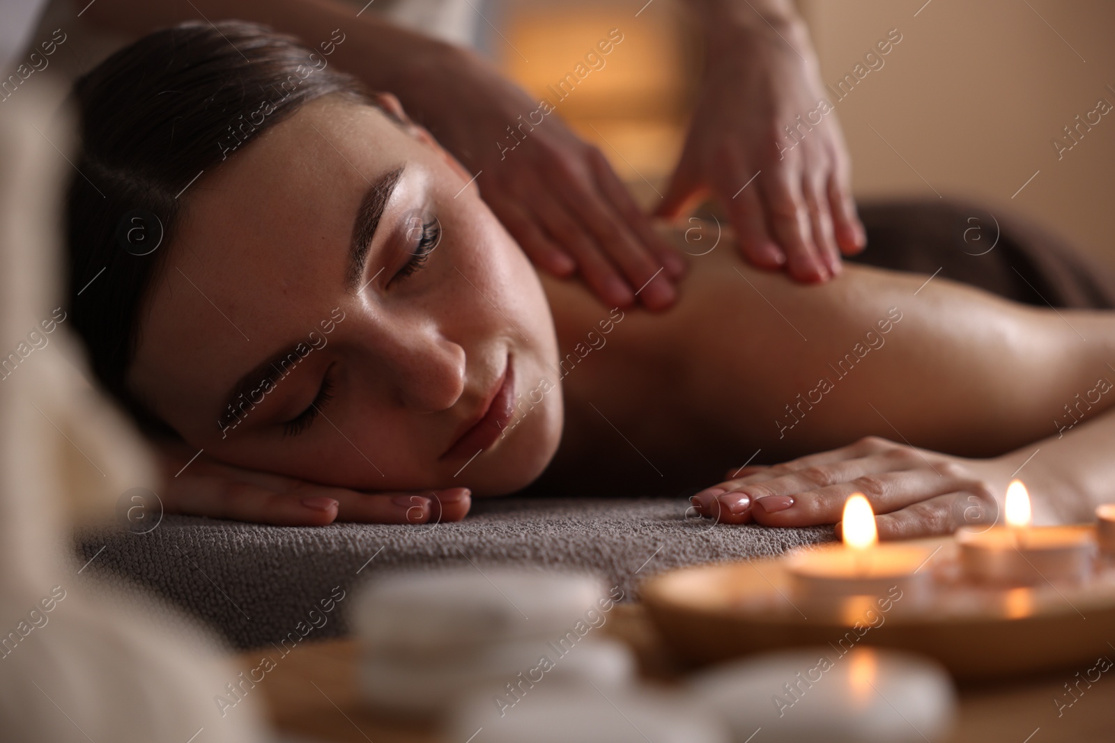 Photo of Spa therapy. Beautiful young woman lying on table during massage in salon, closeup