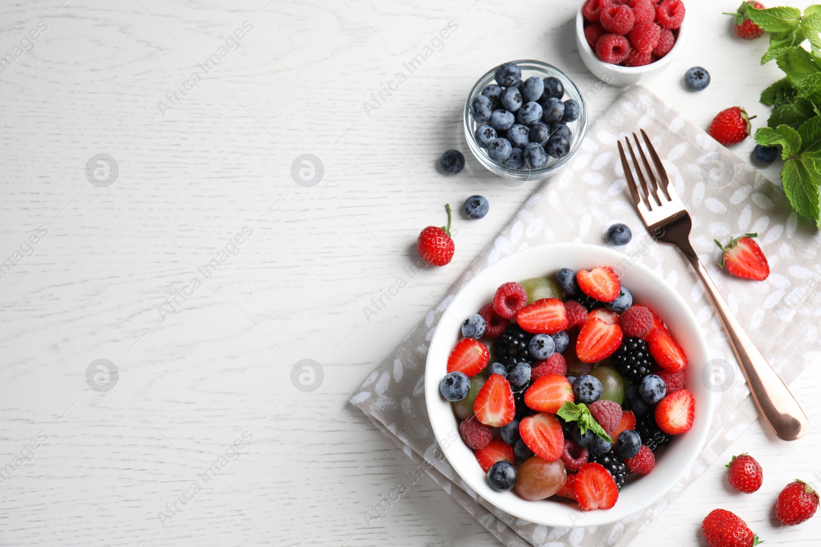 Photo of Fresh tasty fruit salad on white wooden table, flat lay. Space for text