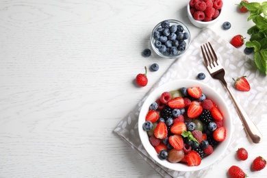 Fresh tasty fruit salad on white wooden table, flat lay. Space for text