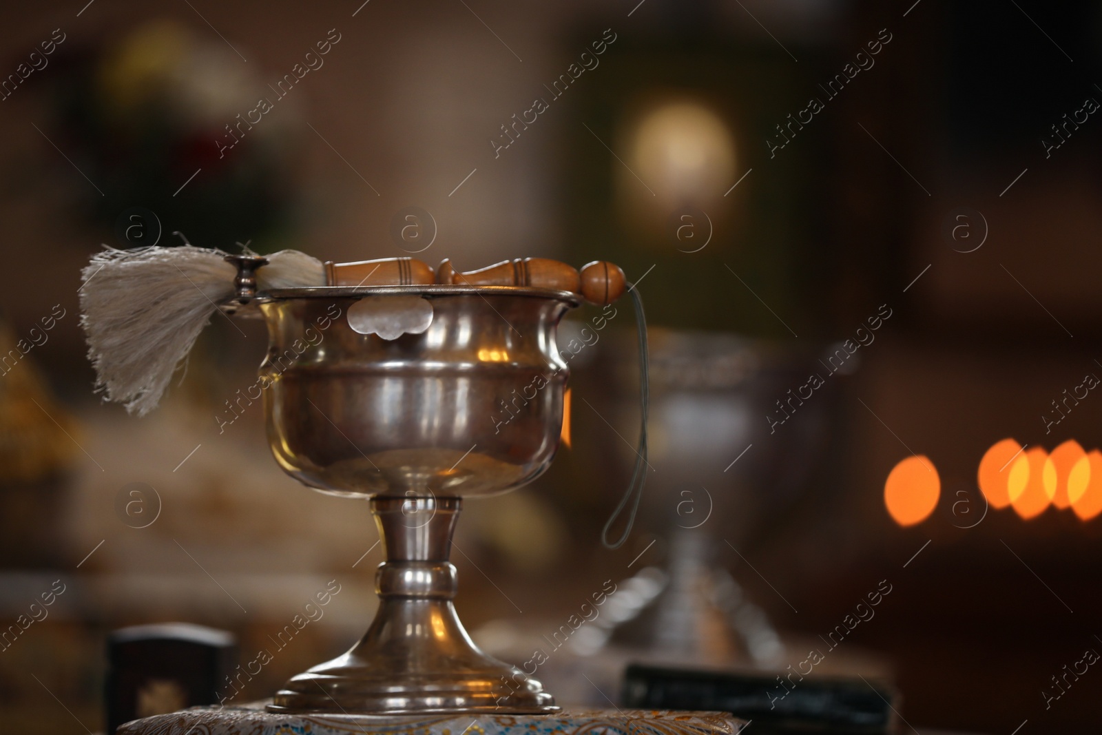 Photo of Silver vessel with holy water and brush on stand in church, space for text. Baptism ceremony