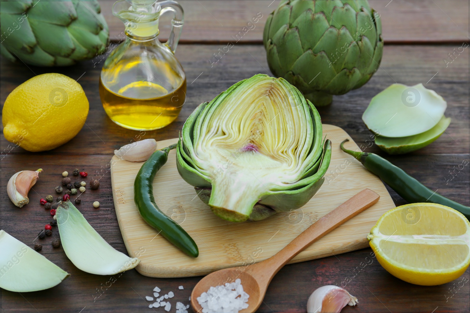Photo of Artichokes, oil and lemons on wooden table