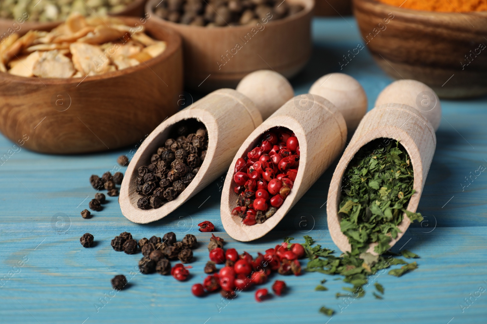 Photo of Scoops with different spices on light blue wooden table