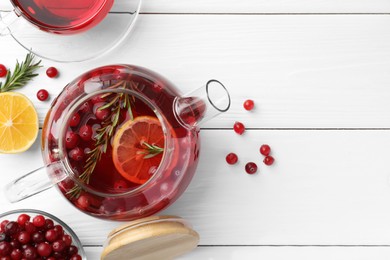 Photo of Tasty hot cranberry tea with lemon, rosemary and fresh berries on white wooden table