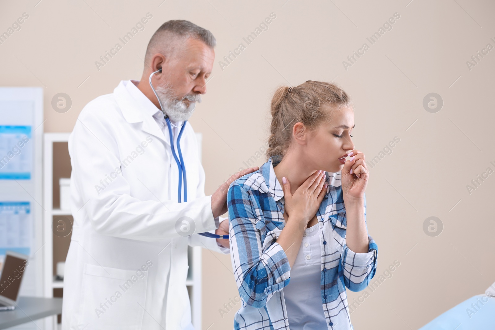 Photo of Doctor examining coughing young woman at clinic