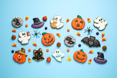 Photo of Tasty cookies and sweets for Halloween party on light blue background, flat lay