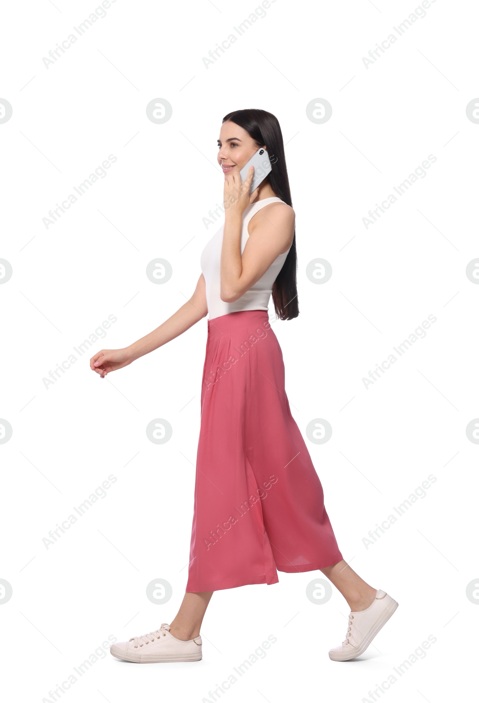 Photo of Young woman talking on smartphone while walking against white background