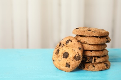 Photo of Stack of tasty chocolate chip cookies on wooden table. Space for text