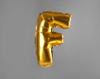 Golden letter F balloon on grey background