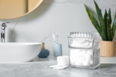 Cotton pads and balls on light grey marble table in bathroom