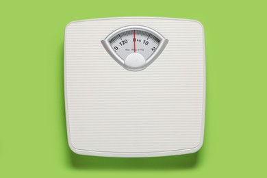 Photo of Bathroom scale on light green background, top view