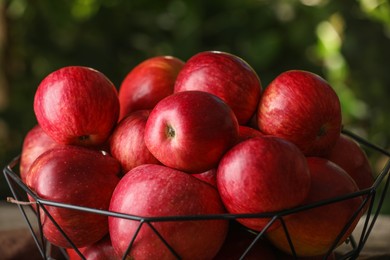 Ripe red apples in bowl on blurred background, closeup