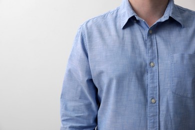 Man wearing light blue shirt on white background, closeup